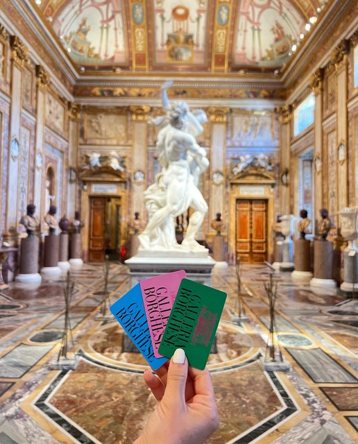 Three Galleria Borghese membership cards held up in the villa's main hall, in front of Bernini's Pluto and Proserpina.
